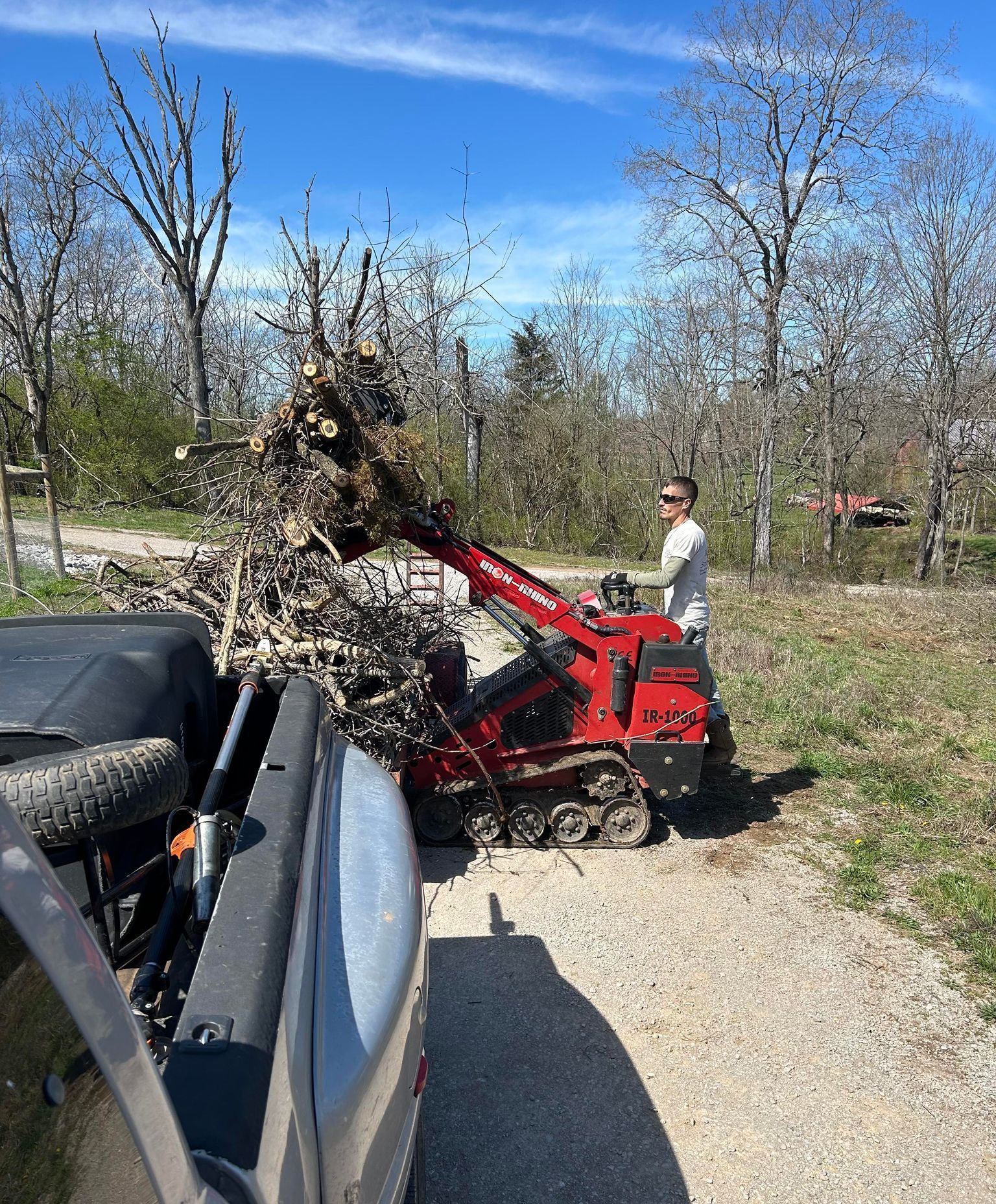 A man is loading a pile of branches into a truck.