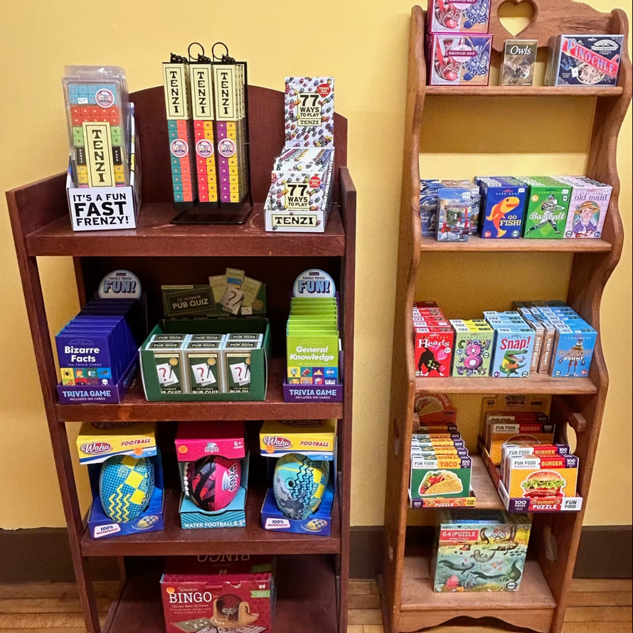 Two wooden shelves display assorted colorful snack boxes and candy in a small shop.