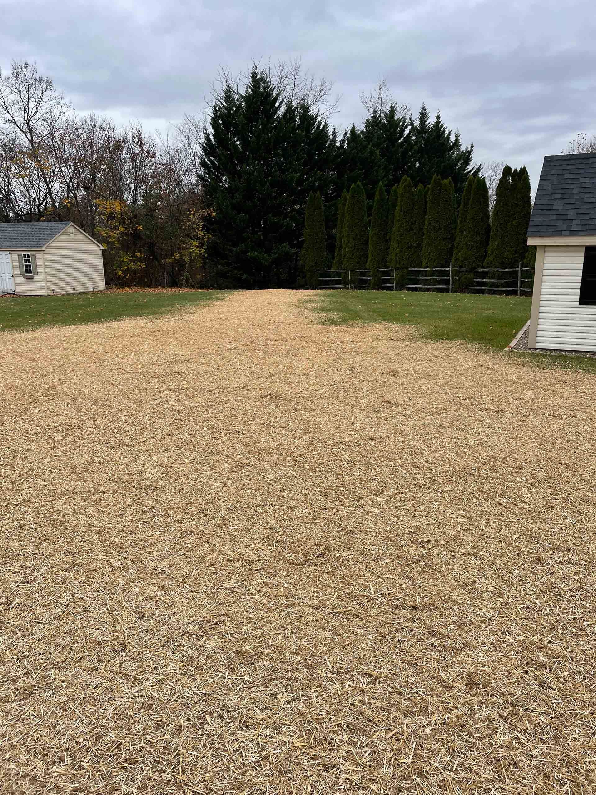 A pile of wood chips in a driveway next to a house.