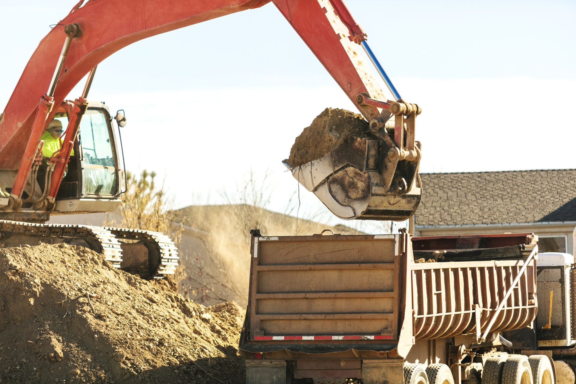 An excavator is loading dirt into a dump truck