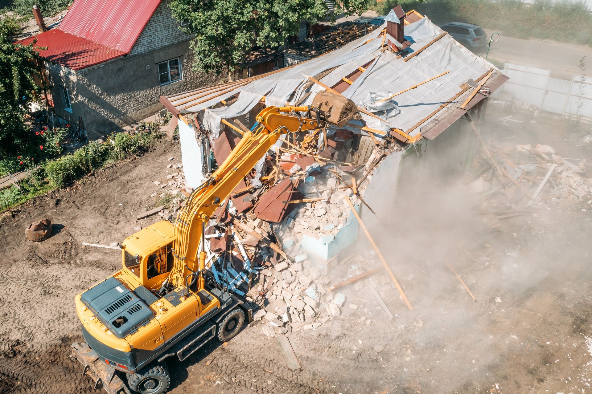 An aerial view of a house being demolished by a bulldozer.