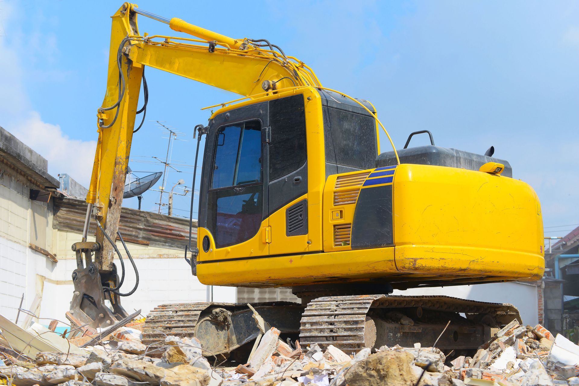 A yellow excavator is demolishing a building.