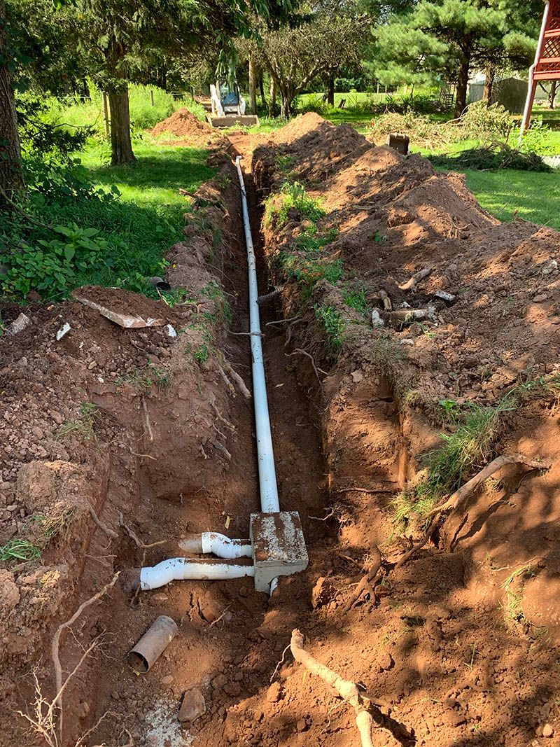 A pipe is being installed in a trench in the dirt.