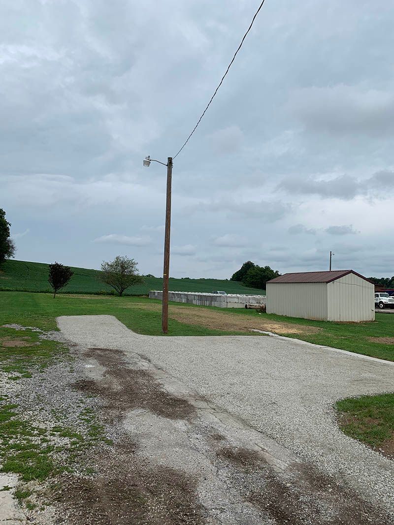 A dirt road with a telephone pole in the middle of it.