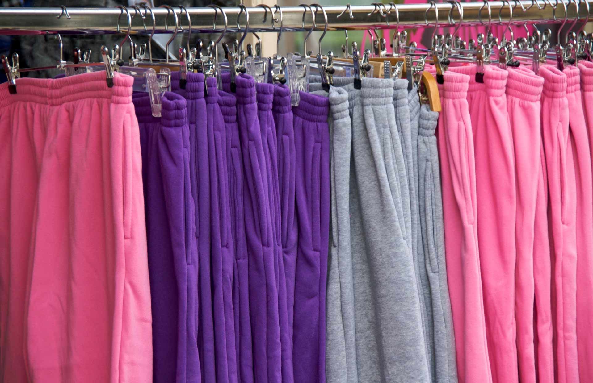 Rows of pink, purple, and gray pants hanging on a clothing rack
