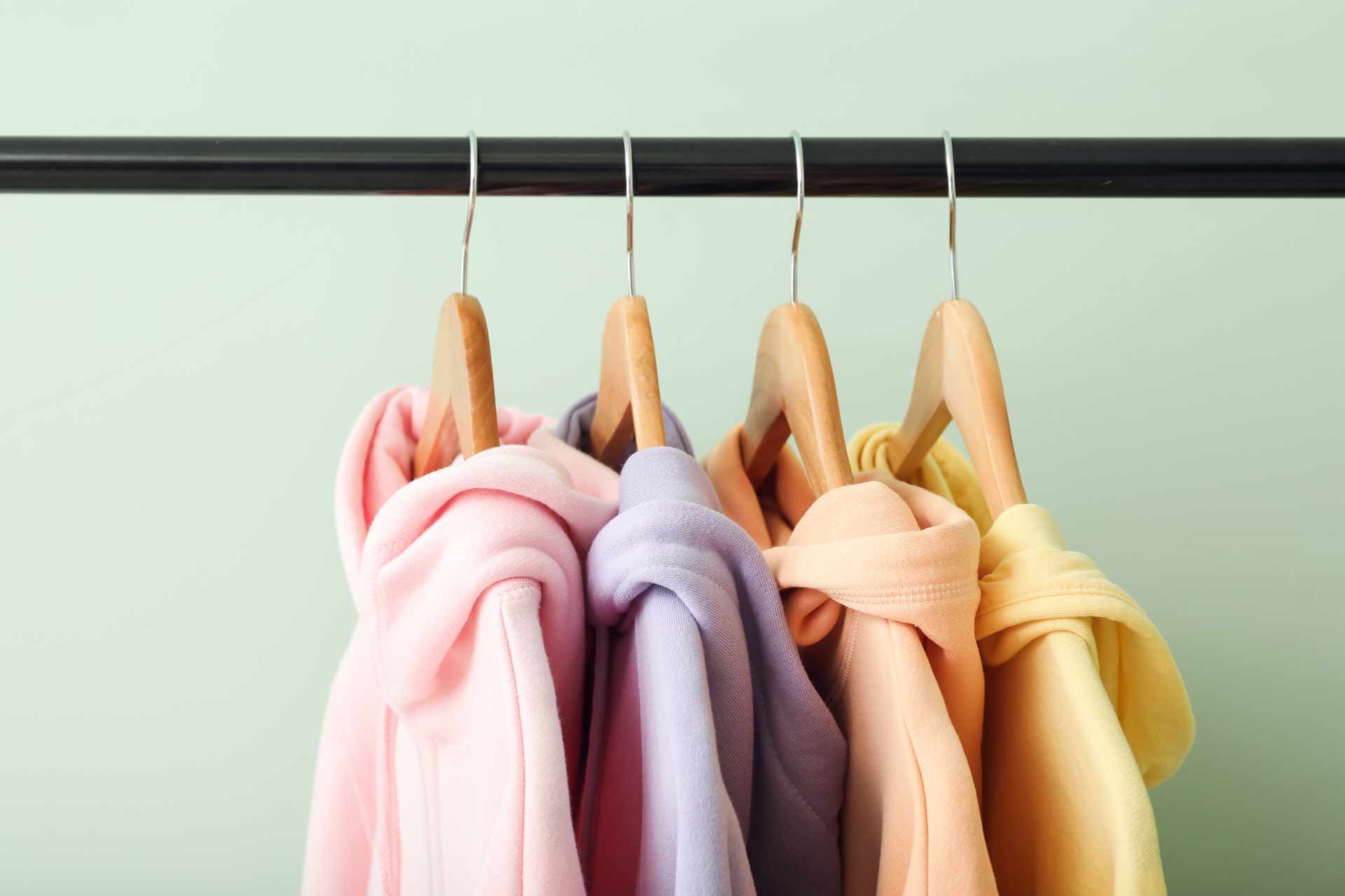 Pastel bathrobes hanging on wooden hangers on a black rack
