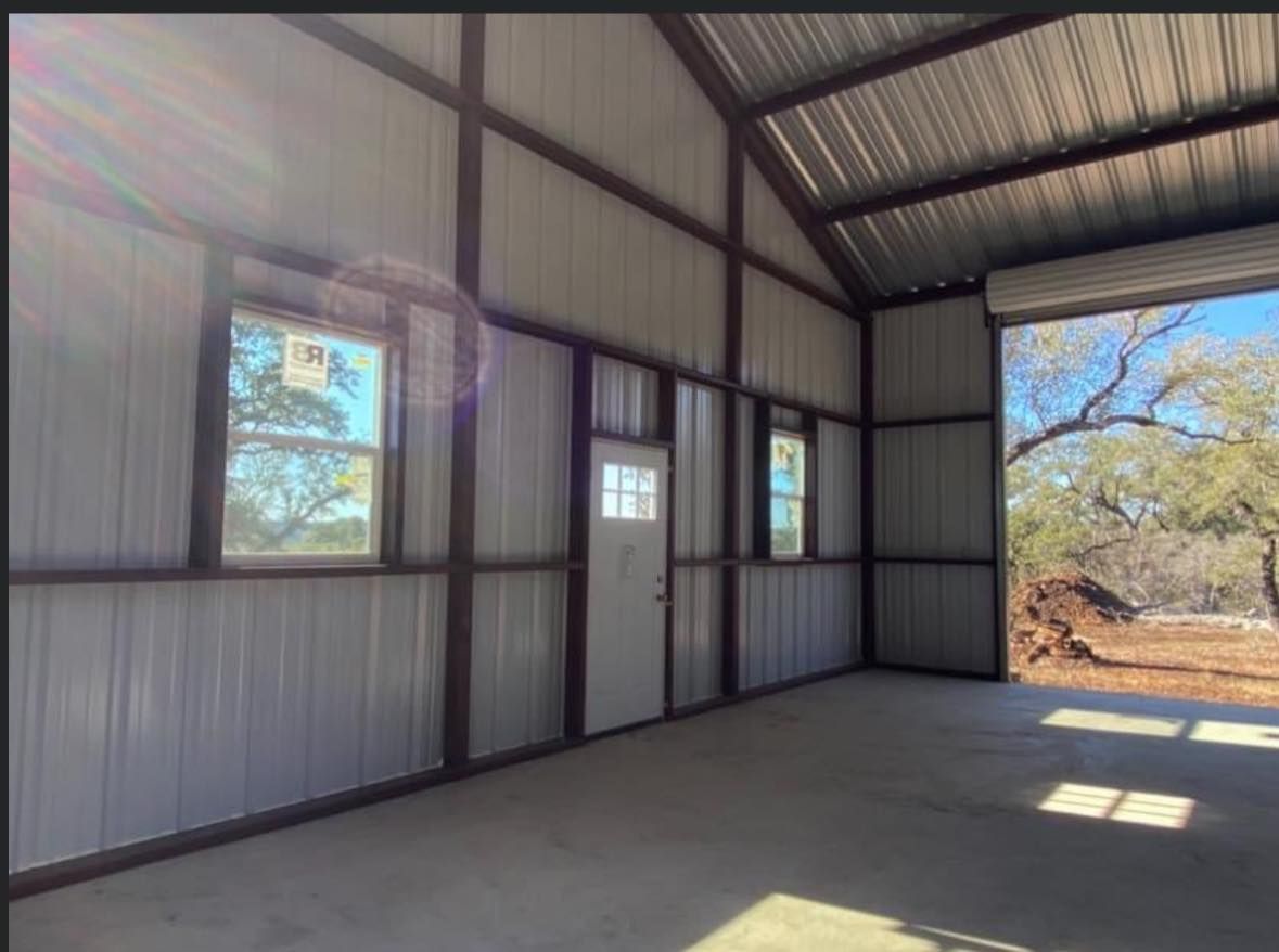 Interior of a metal building with a concrete floor, windows, a door, and a roll-up door.