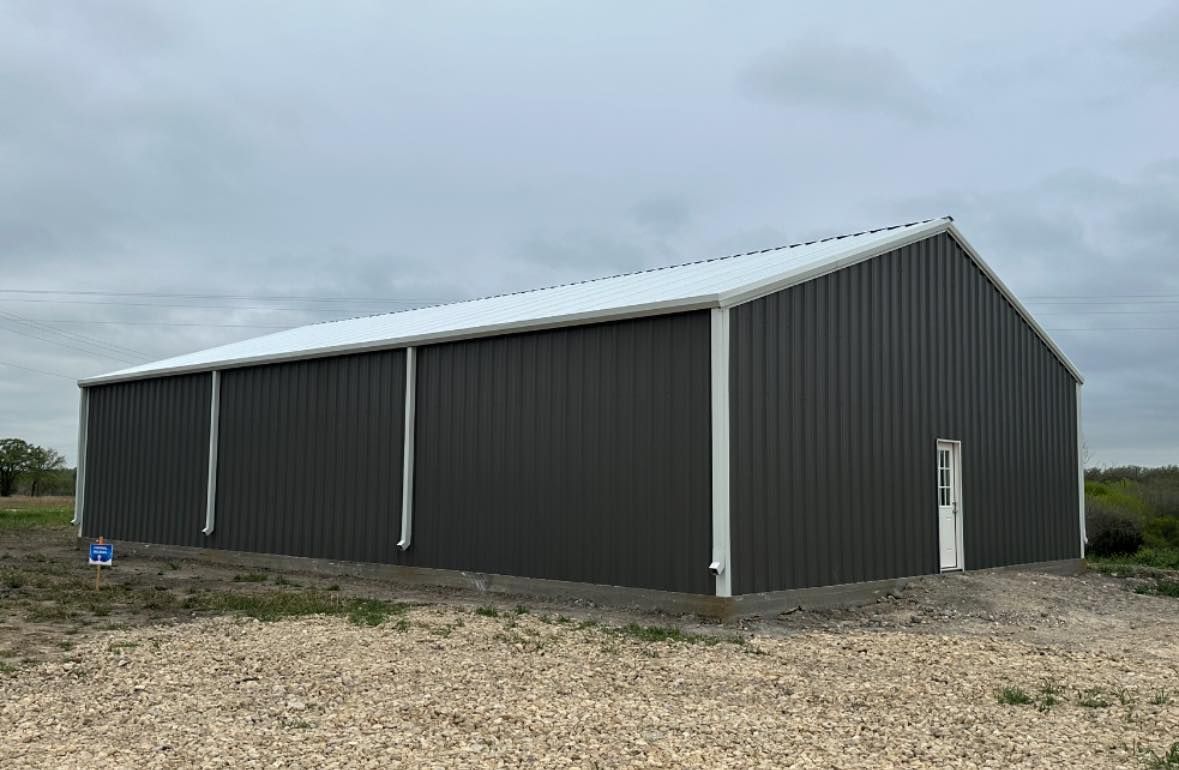 Large gray metal building with white trim under an overcast sky.
