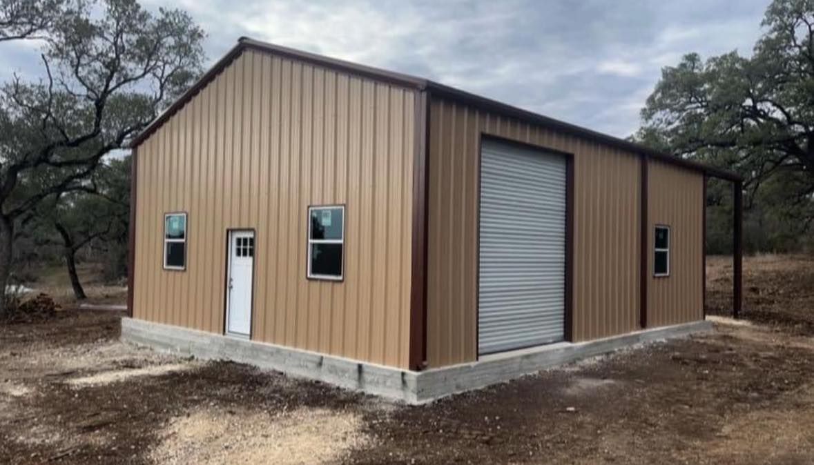 Tan metal building with brown trim, a large garage door, windows, and a doorway.