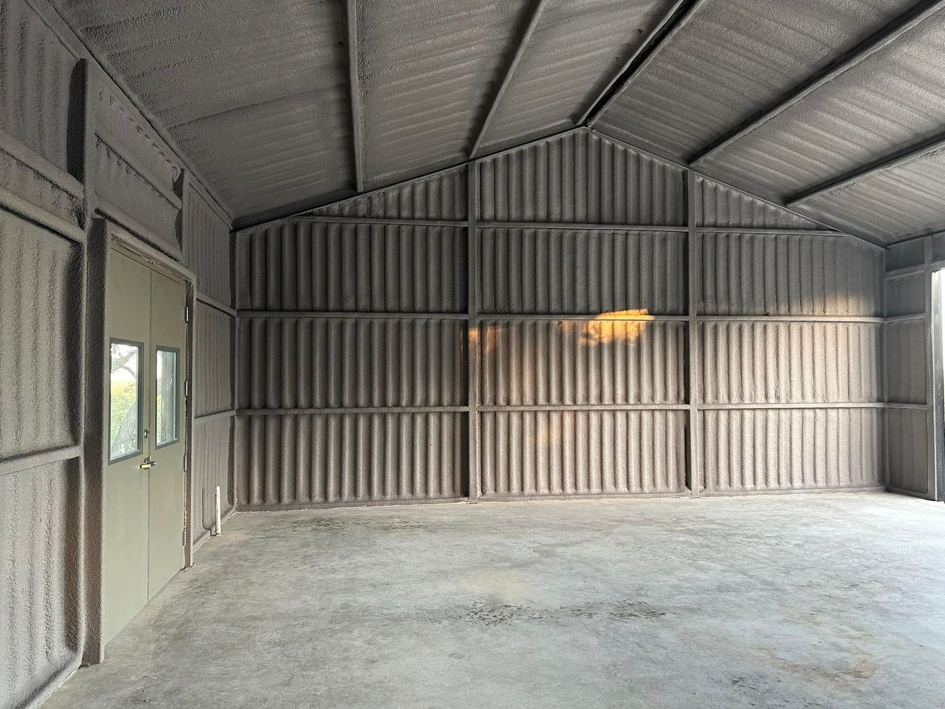 Interior view of a gray metal shed with a slanted roof and concrete floor.