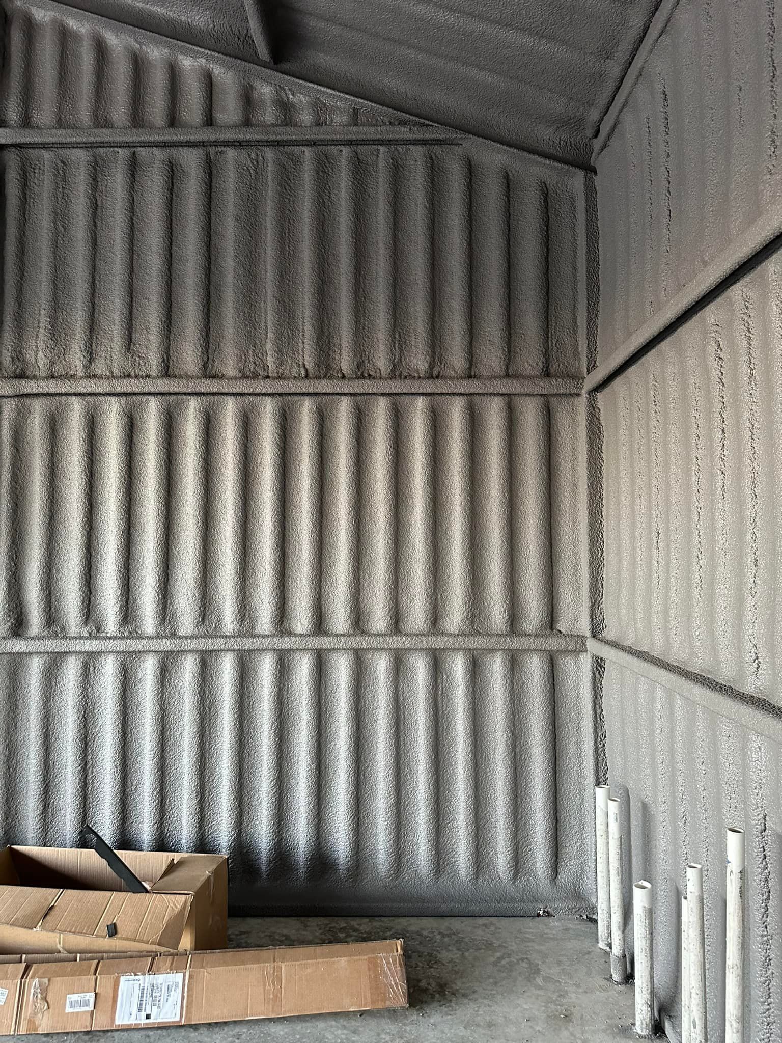 Interior of a corrugated metal storage shed, weathered and gray, with a few cardboard boxes on the floor.