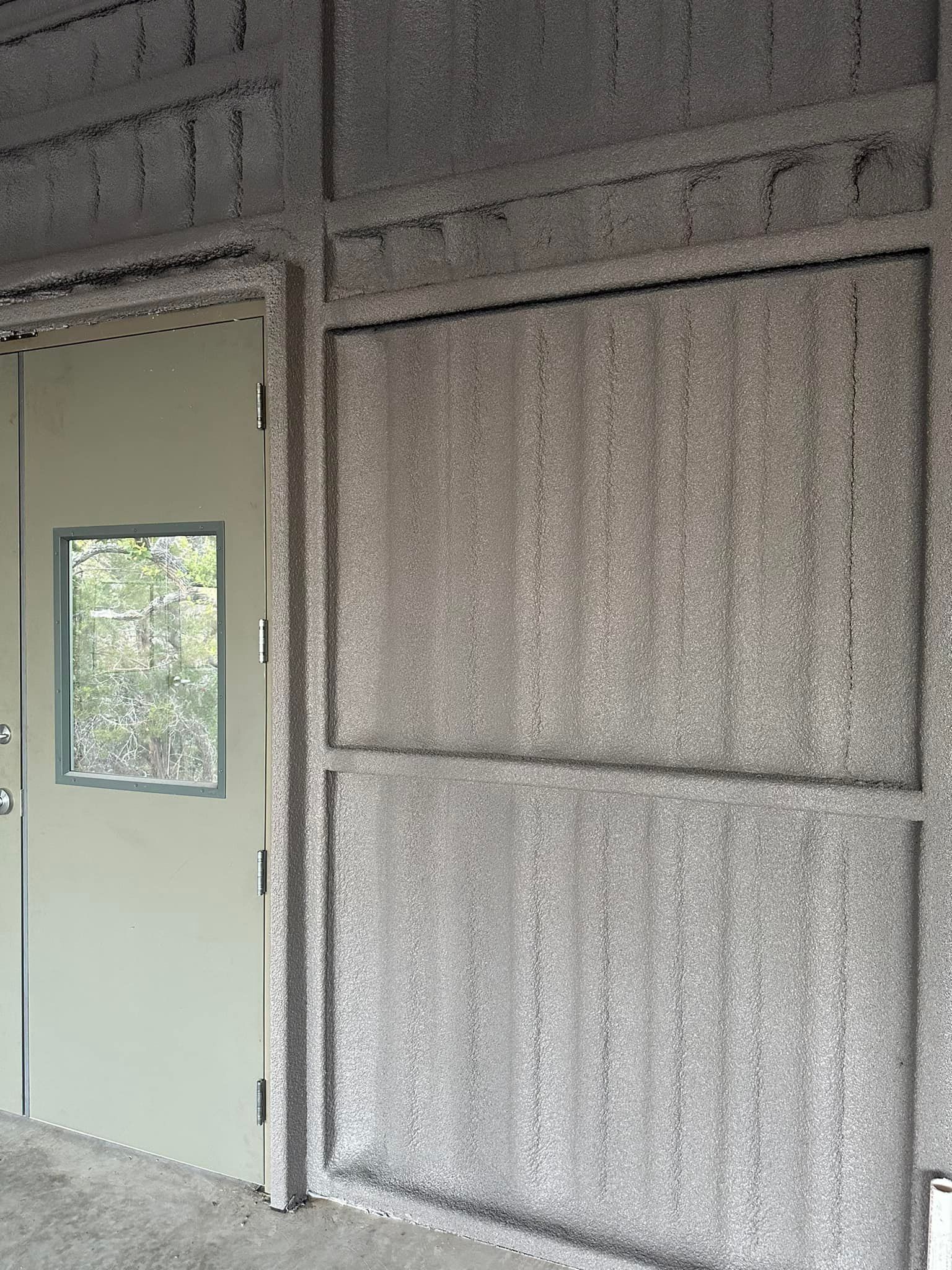 Exterior of a building with a door and a screened window. Walls and door are greyish-beige.