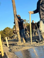 Construction workers pouring concrete from a large hose into a form outdoors.