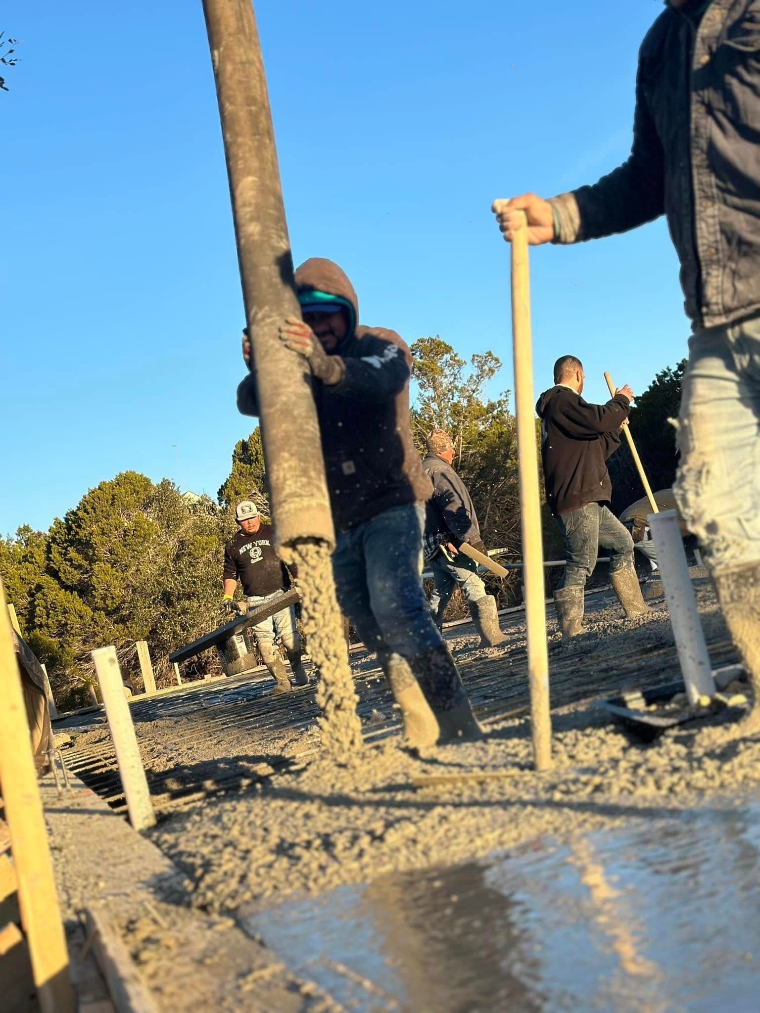 Construction workers pouring concrete on a sunny day.