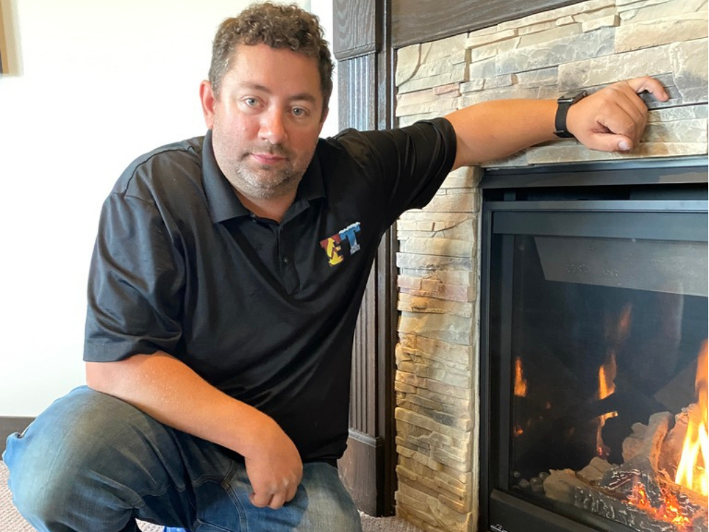 Full Time Heating & Cooling | A man is kneeling down in front of a fireplace.