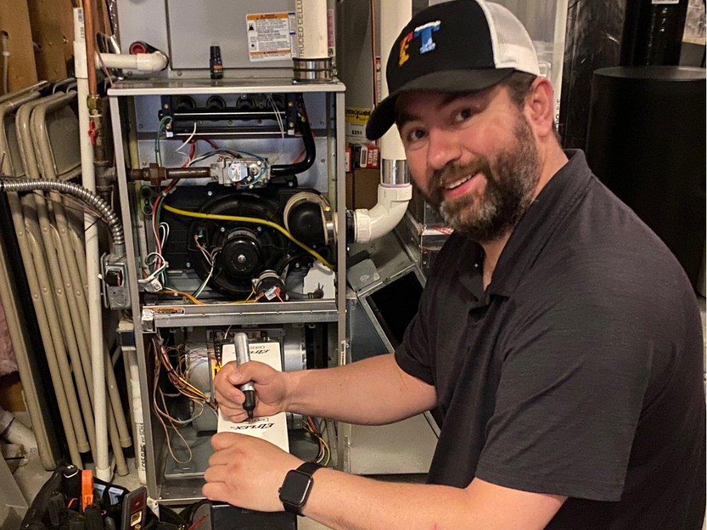 Full Time Heating & Cooling | A man wearing a hat is working on a heating system.