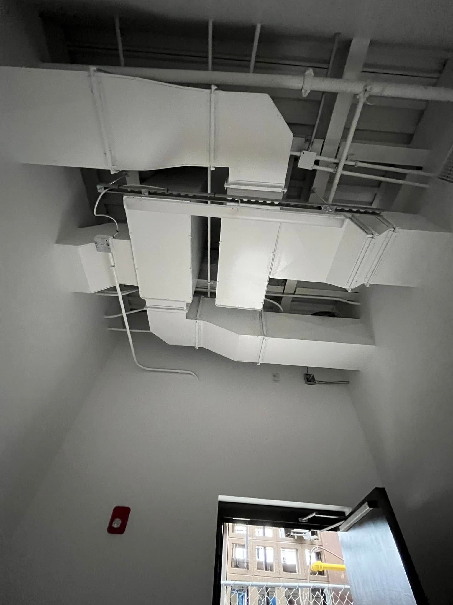 White ceiling with exposed ductwork and a doorway. A fire alarm is visible.
