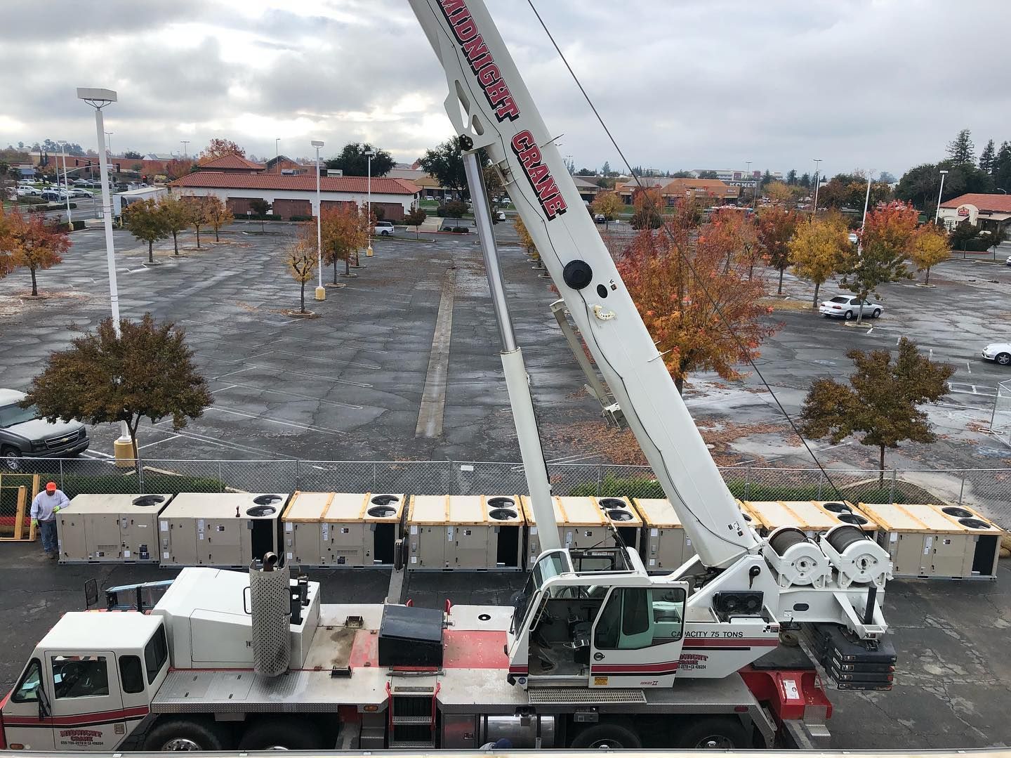 Crane lifting large boxes in a parking lot on an overcast day.