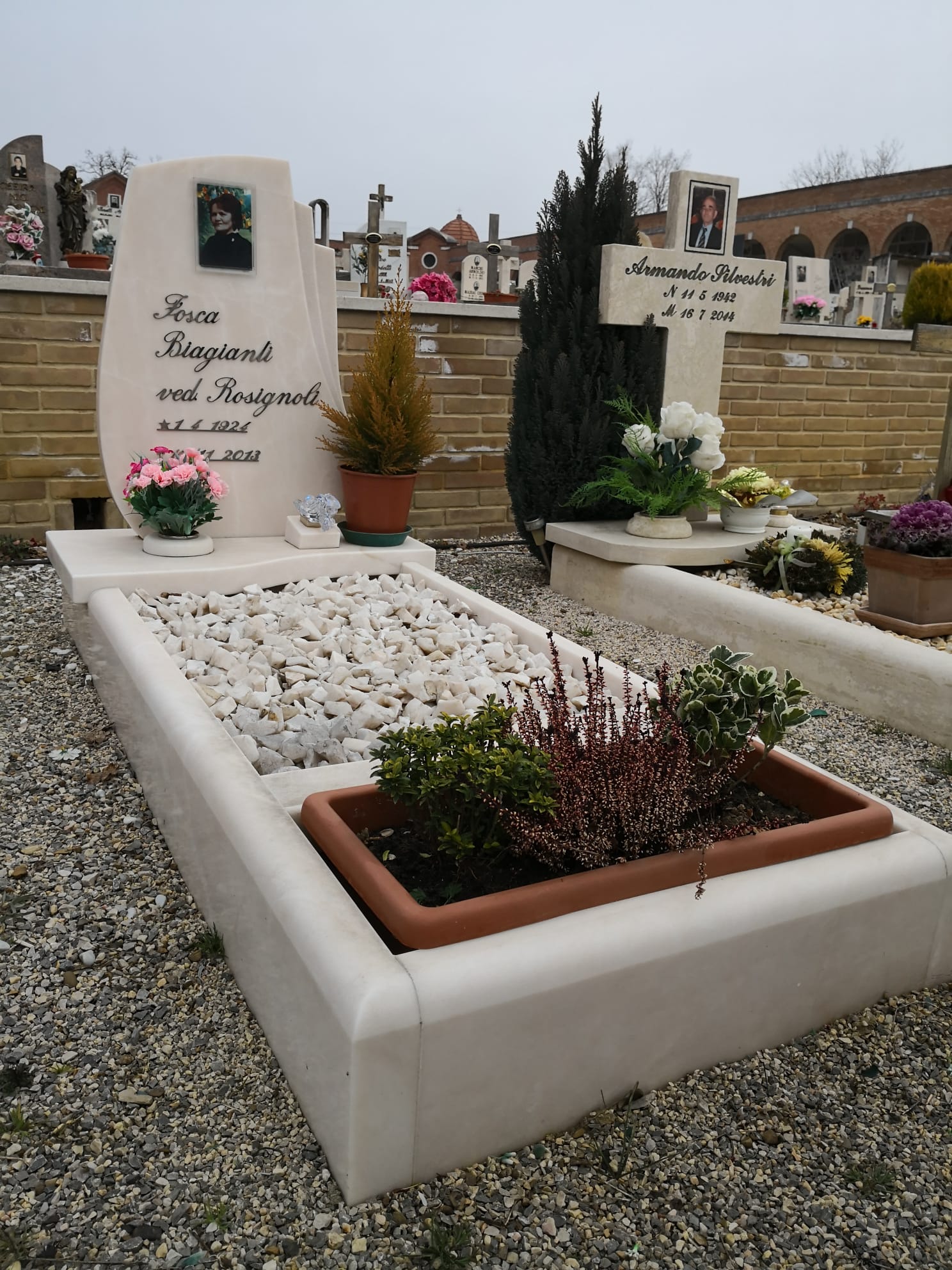 Una tomba in un cimitero con fiori e una croce