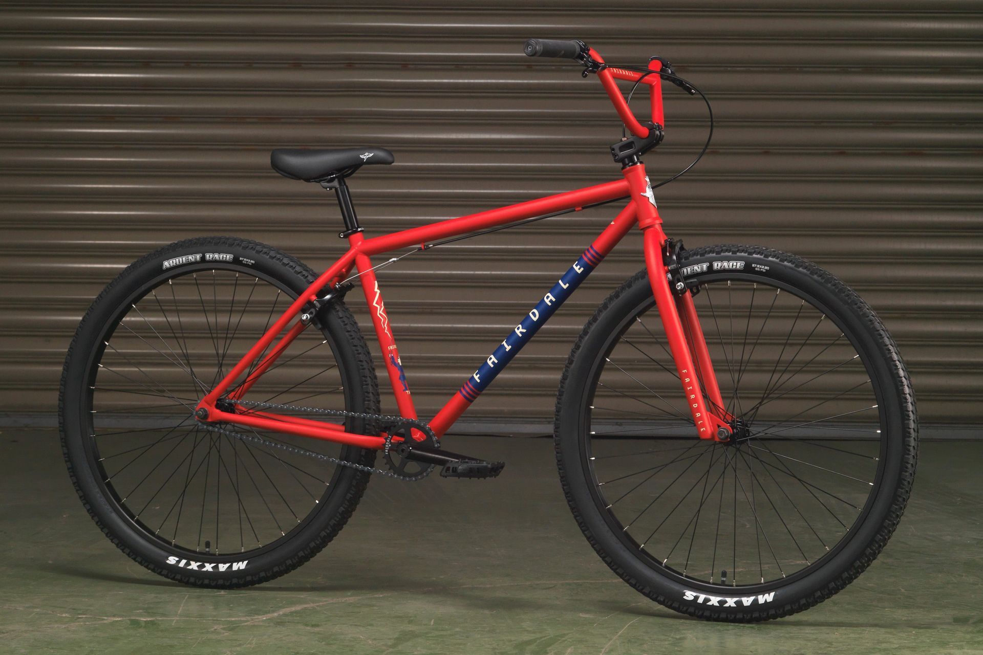 A red bmx bike is parked in front of a garage door.
