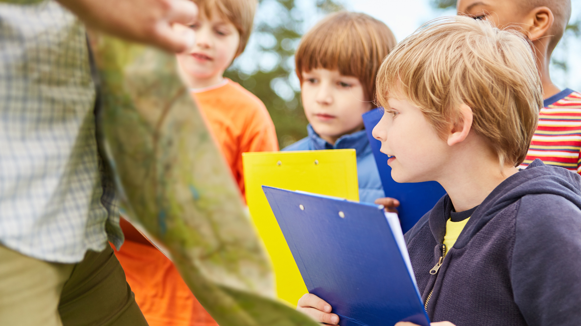 Children studying nature with notebooks, observing a tree trunk in an outdoor setting.
