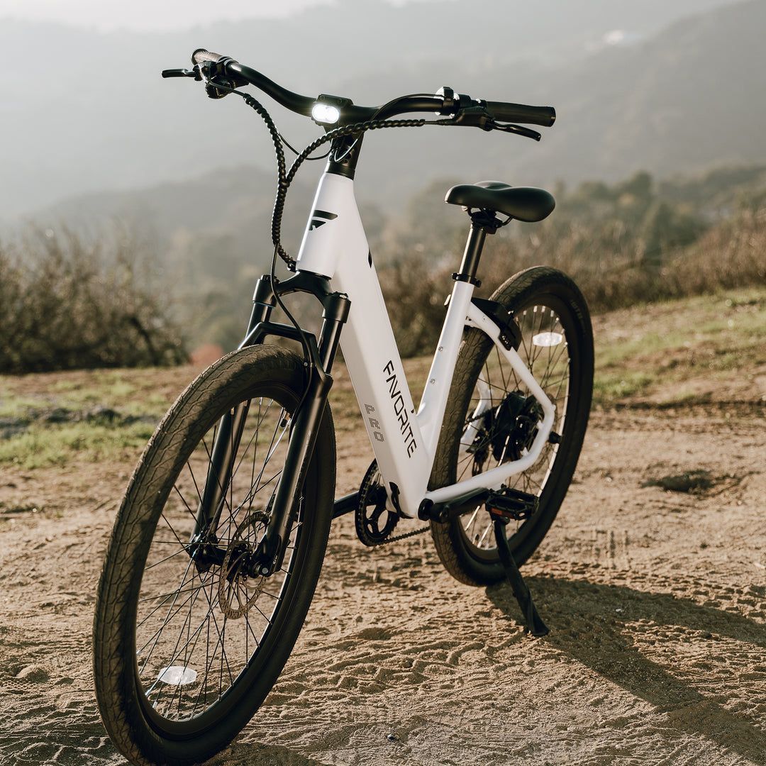A white bicycle is parked on the side of a dirt road.