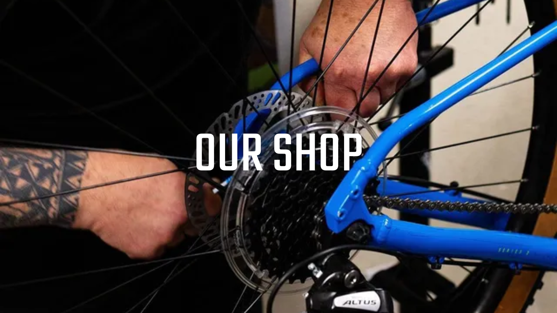 A man is fixing a bicycle with a tattoo on his arm.