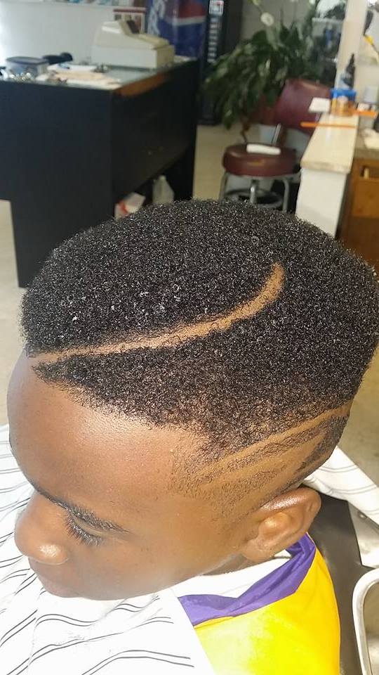 A young boy is getting his hair cut at a barber shop.