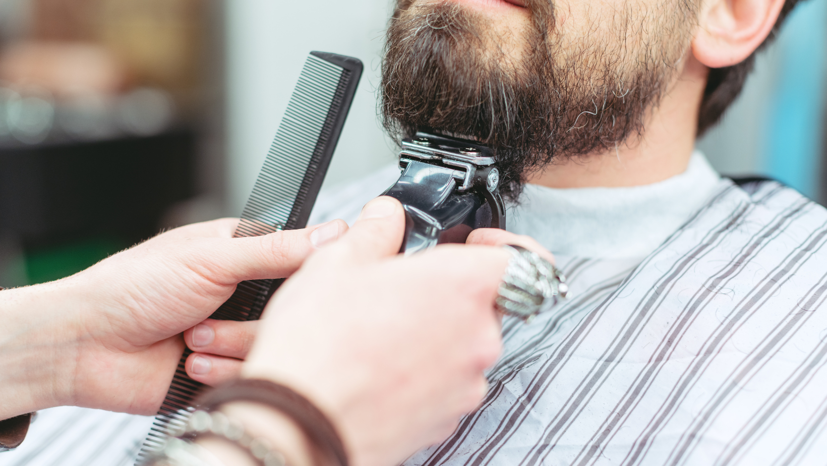 A man is getting his beard trimmed by a barber.