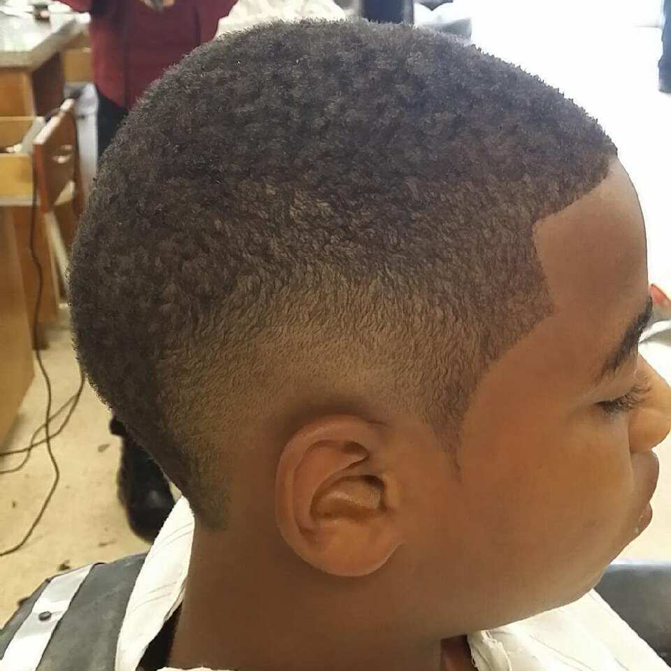 A young boy is getting his hair cut at a barber shop