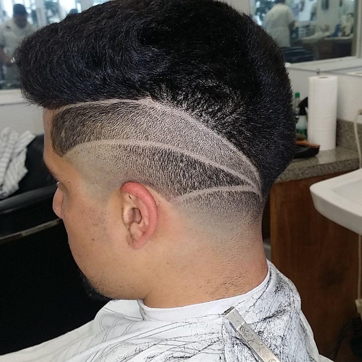 A man is getting his hair cut at a barber shop.