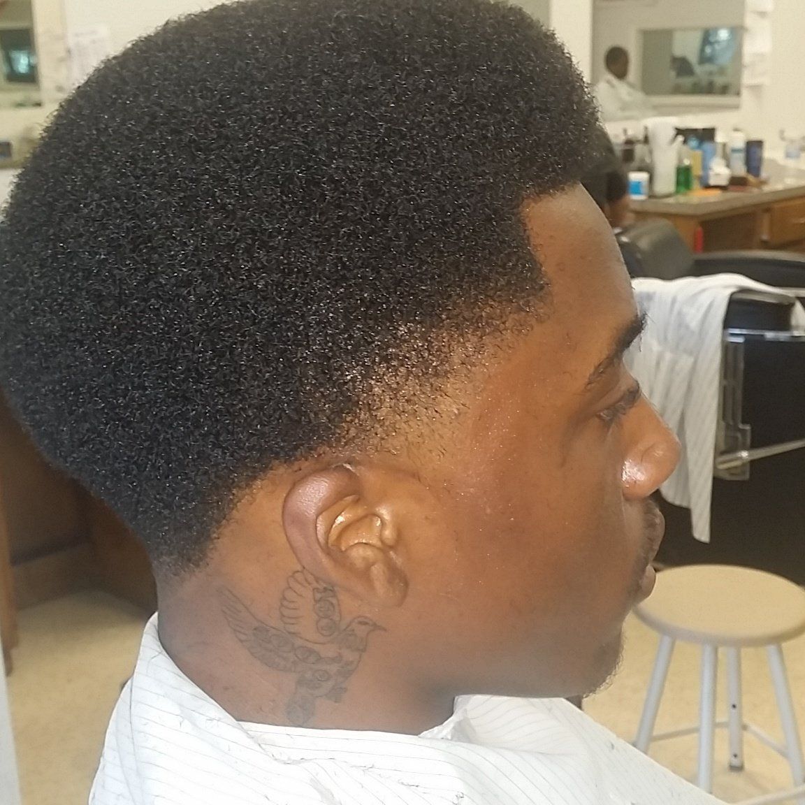 A man with a tattoo on his neck is getting his hair cut