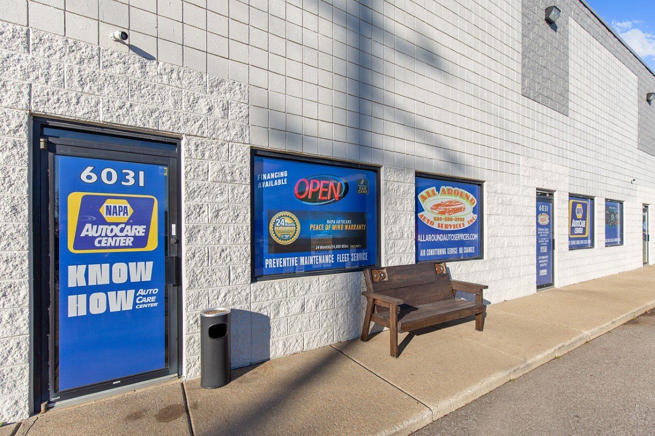 NAPA AutoCare Center building with blue door, windows, and bench. Signage indicates open hours and services.