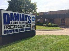 Sign for Damian's Auto Service, blue and white, with phone number and 