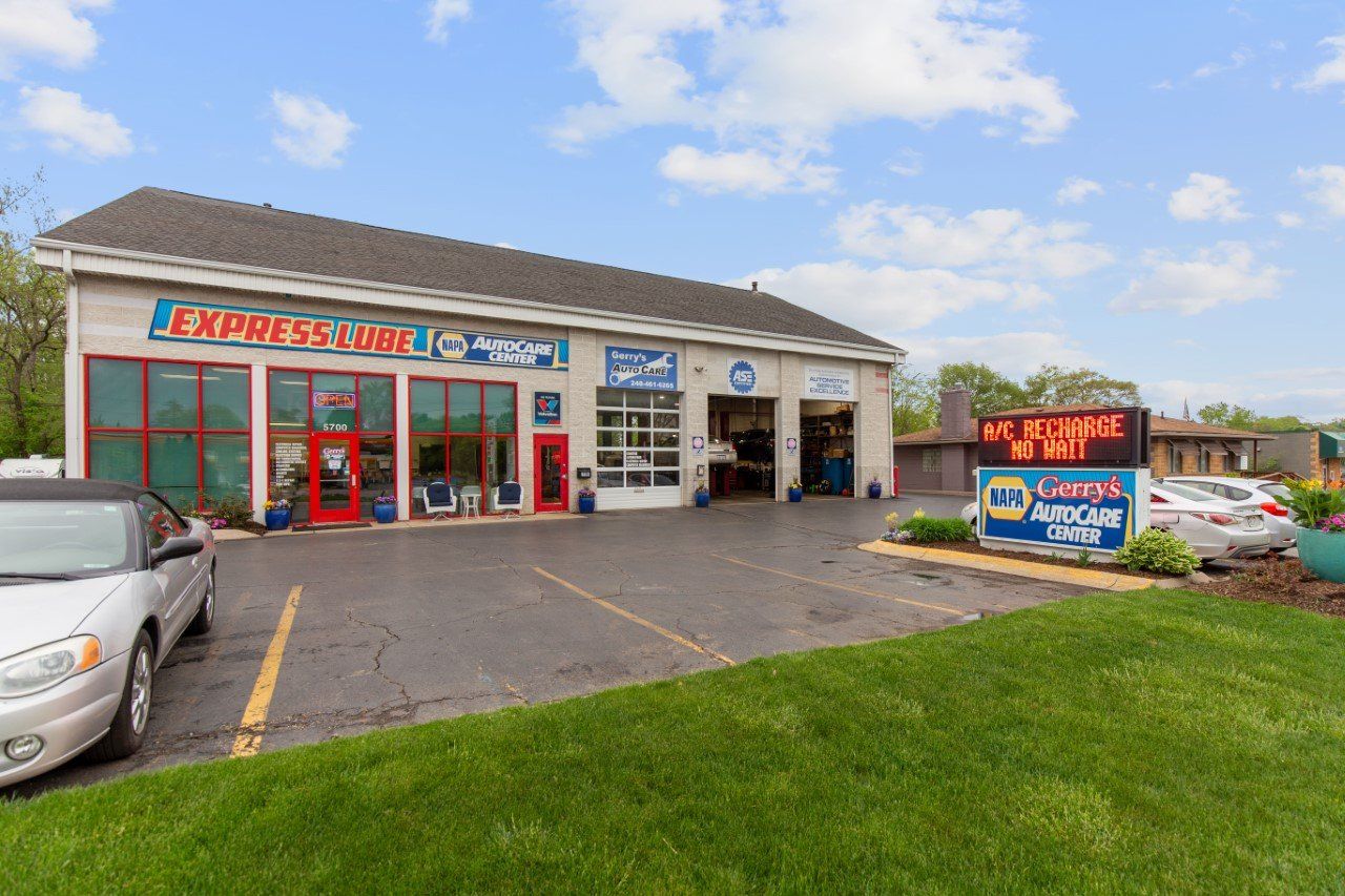 Auto repair shop with green lawn, gray asphalt, and cloudy sky. Signage includes