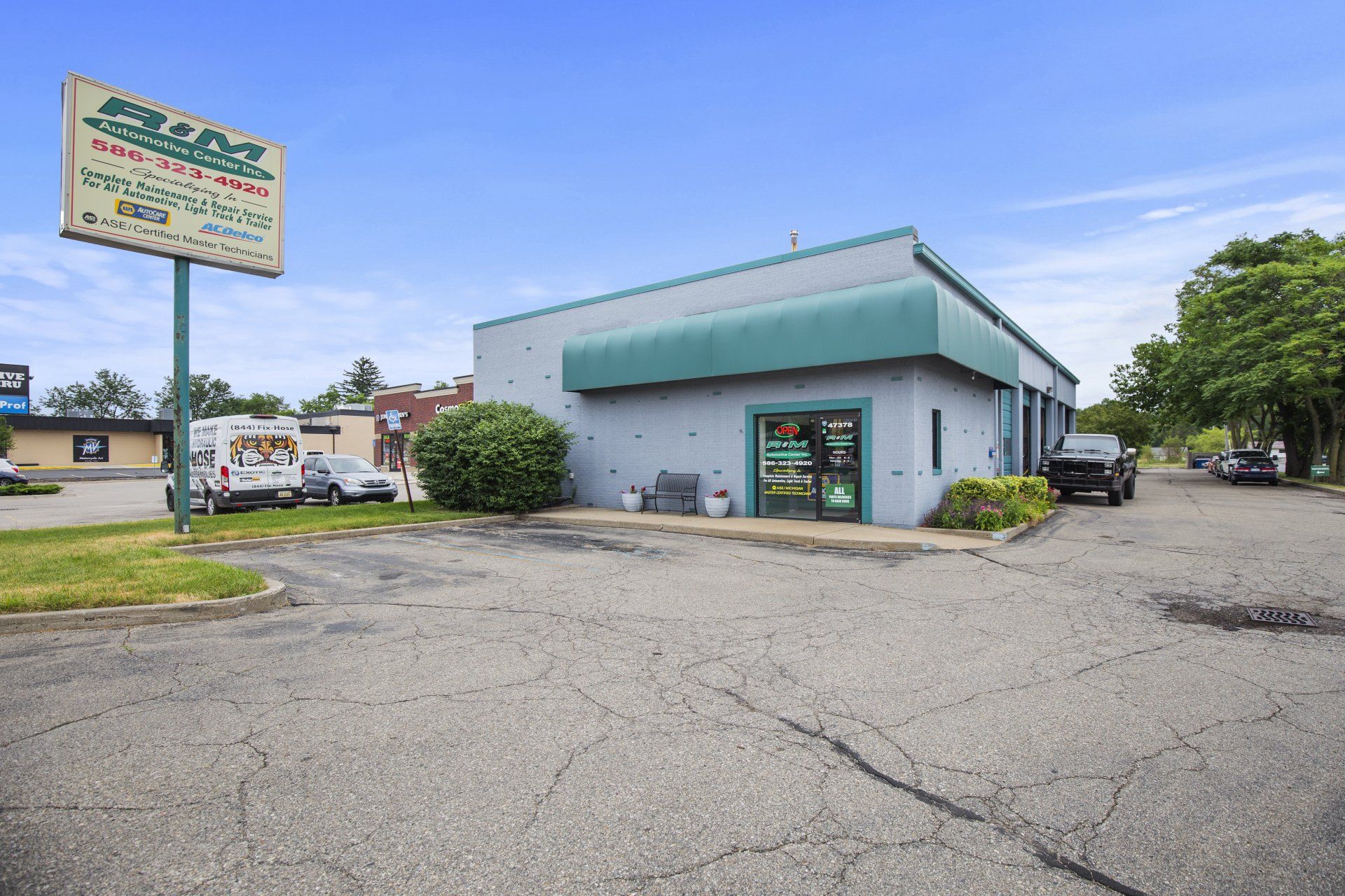Exterior of a auto repair shop with a sign; building is light blue with a green awning and sign.