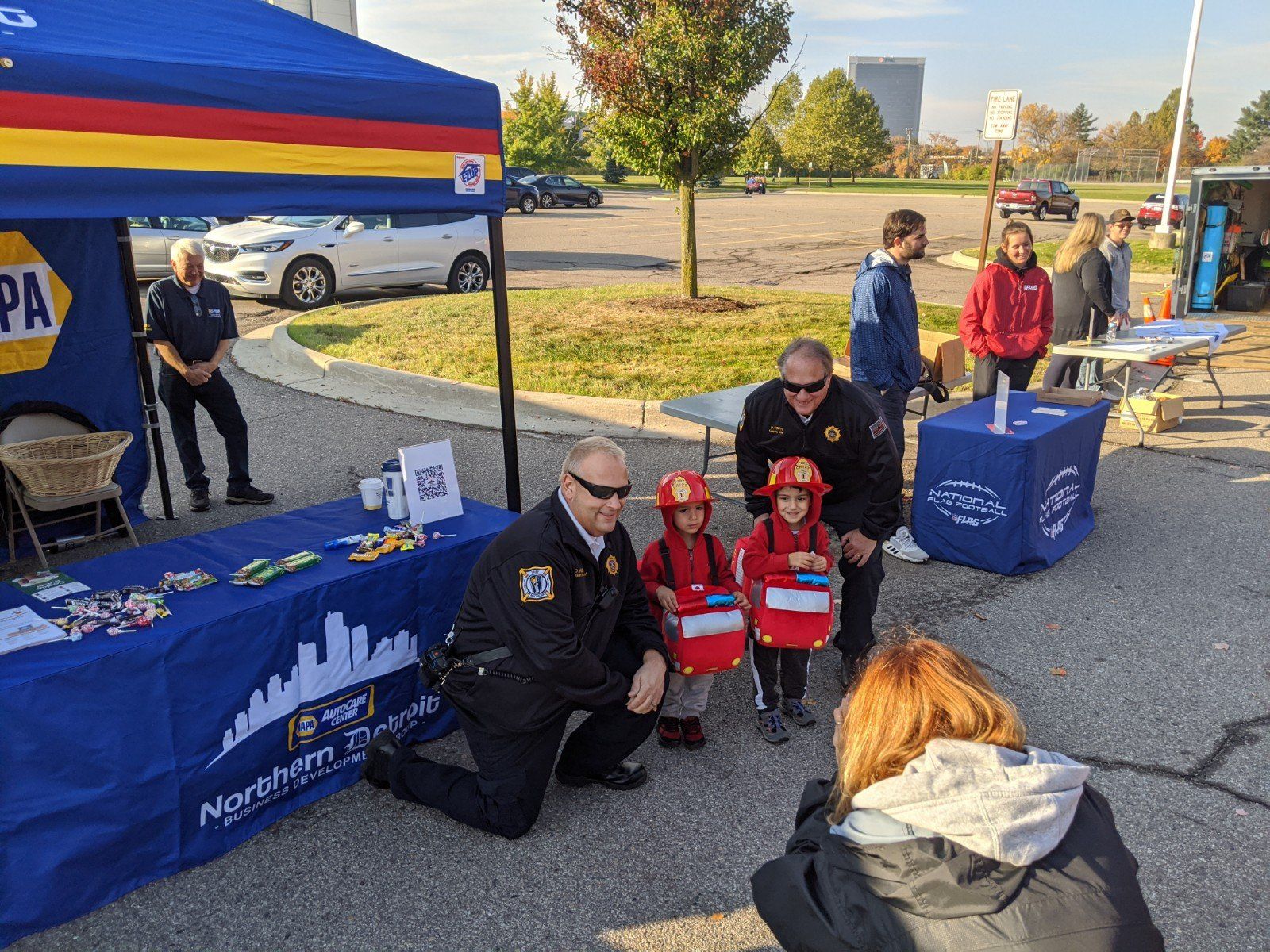 Firefighters posing with children, near an event tent.