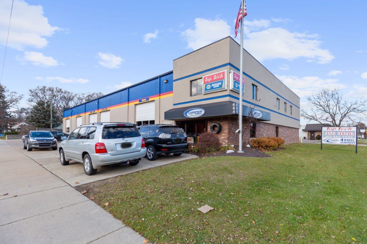 A business building with cars parked out front, American flag flying.