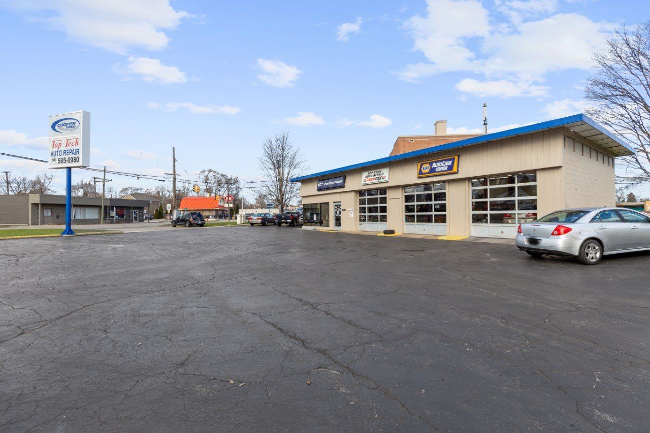 Auto repair shop with parking lot and signage under a blue sky.