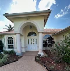 A large white house with a brick walkway leading to the front door.