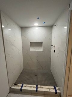 A bathroom with a walk in shower and a shelf in the wall.