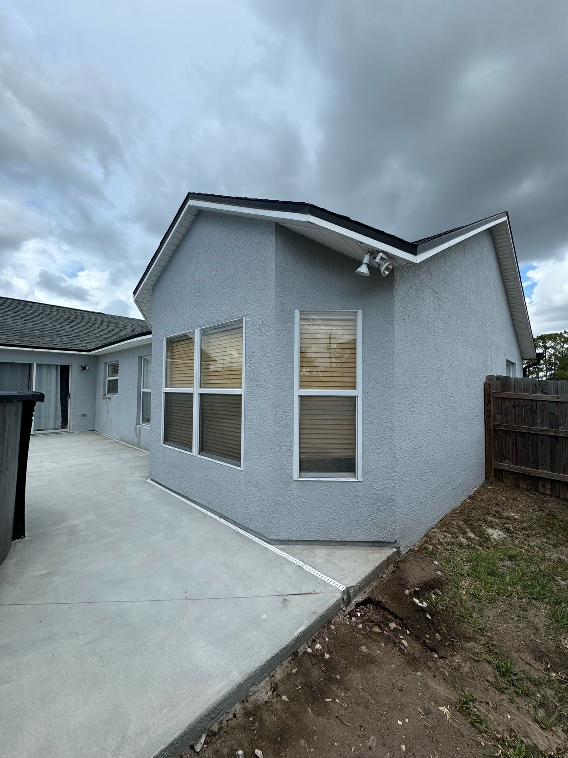 A house with a lot of windows and a fence in the backyard.