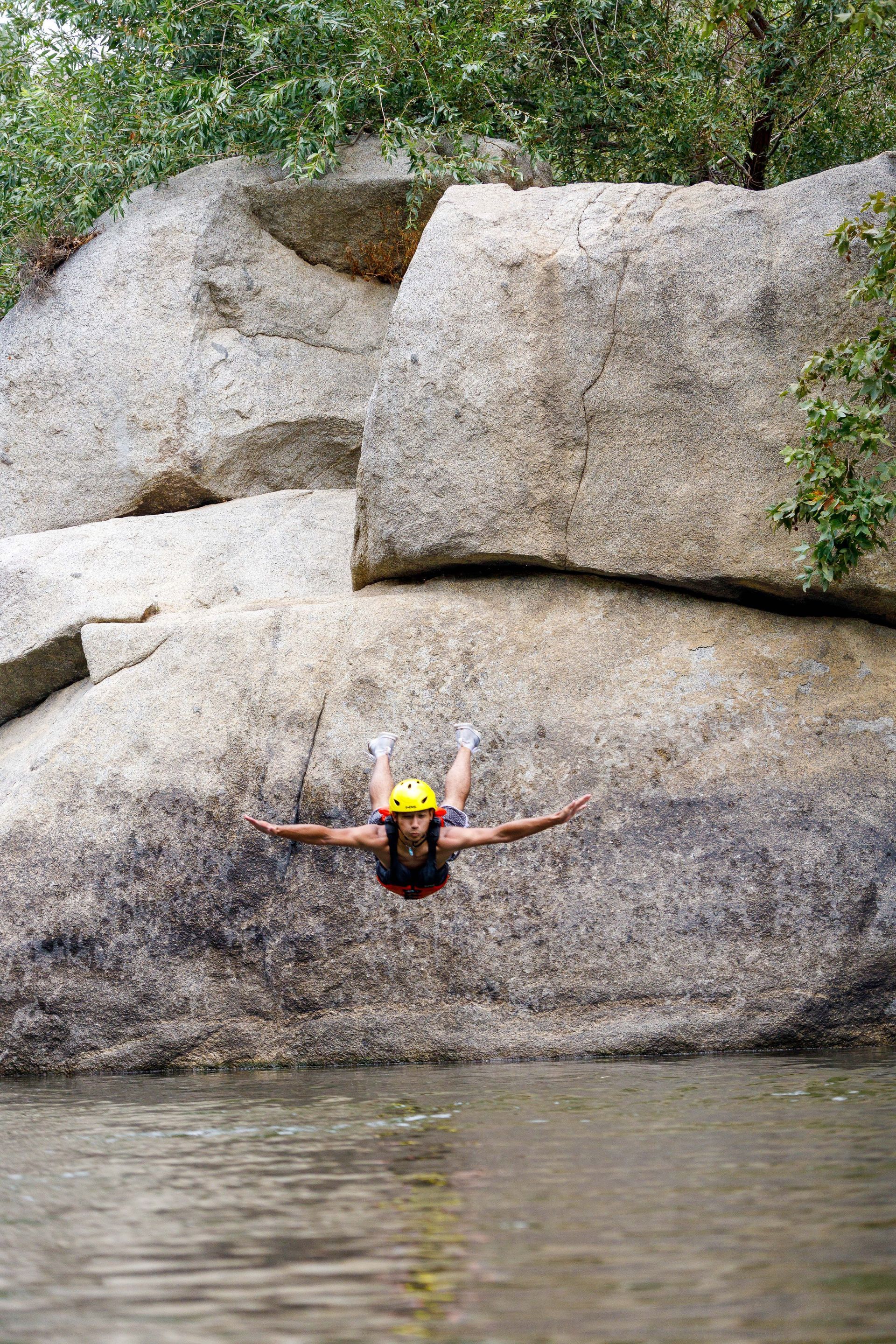 a person jumping off a rock into the kern river