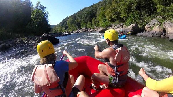2 people in a red rafting going down rapids