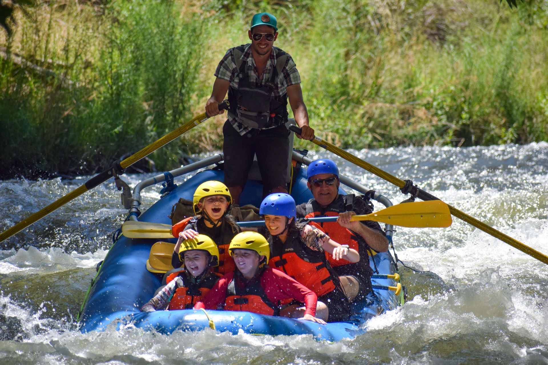 A group of people wearing life jackets are standing around a rock.