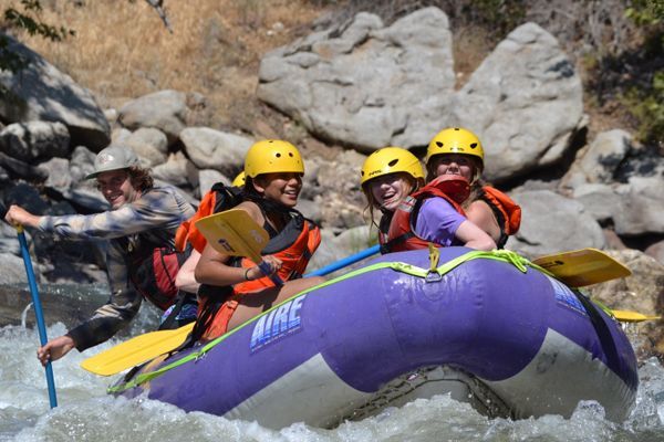 3 girls in a raft going down rapids
