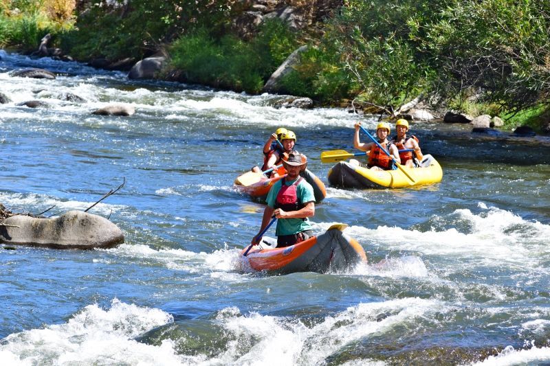 A group of people are rafting down a river in kayaks