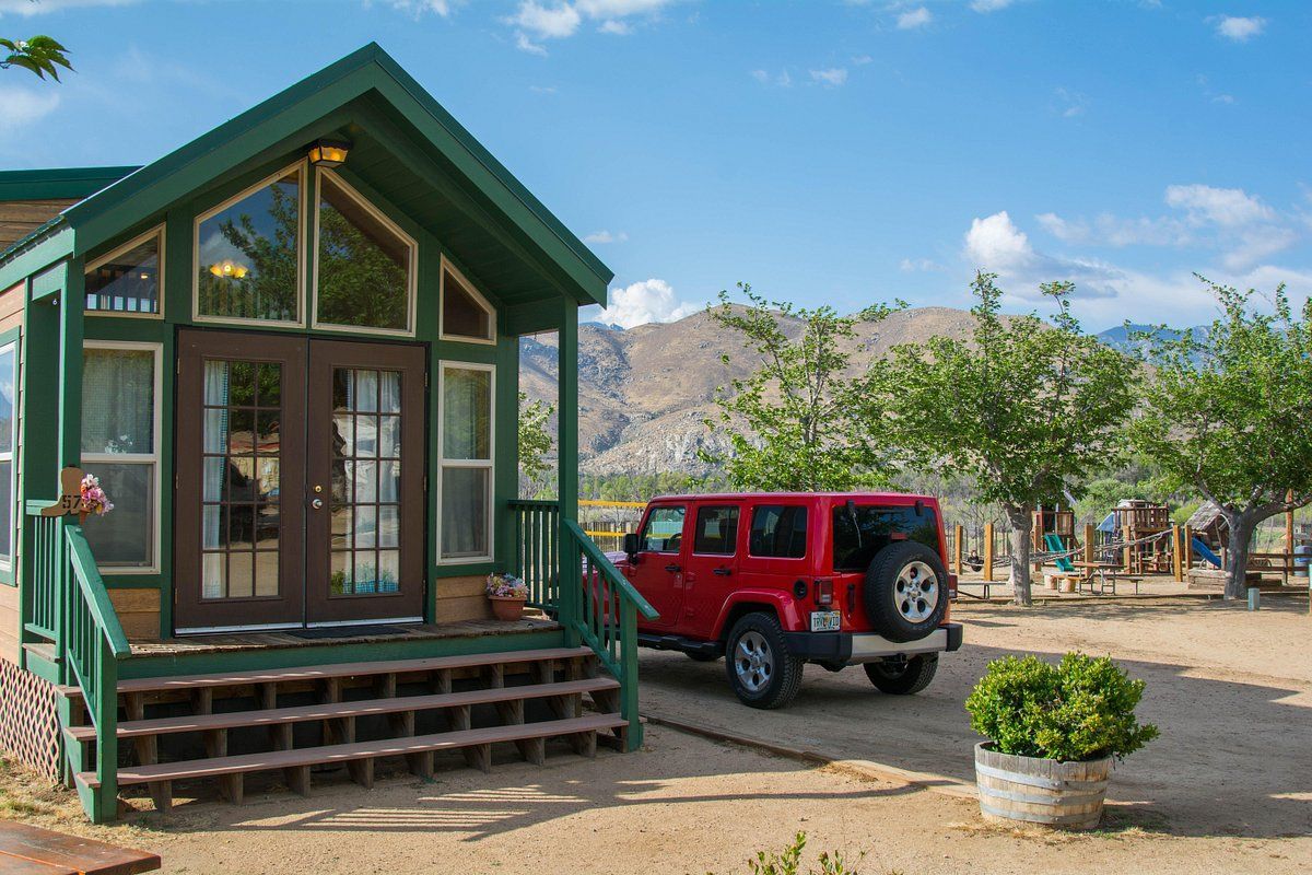 A red jeep is parked in front of a small house.