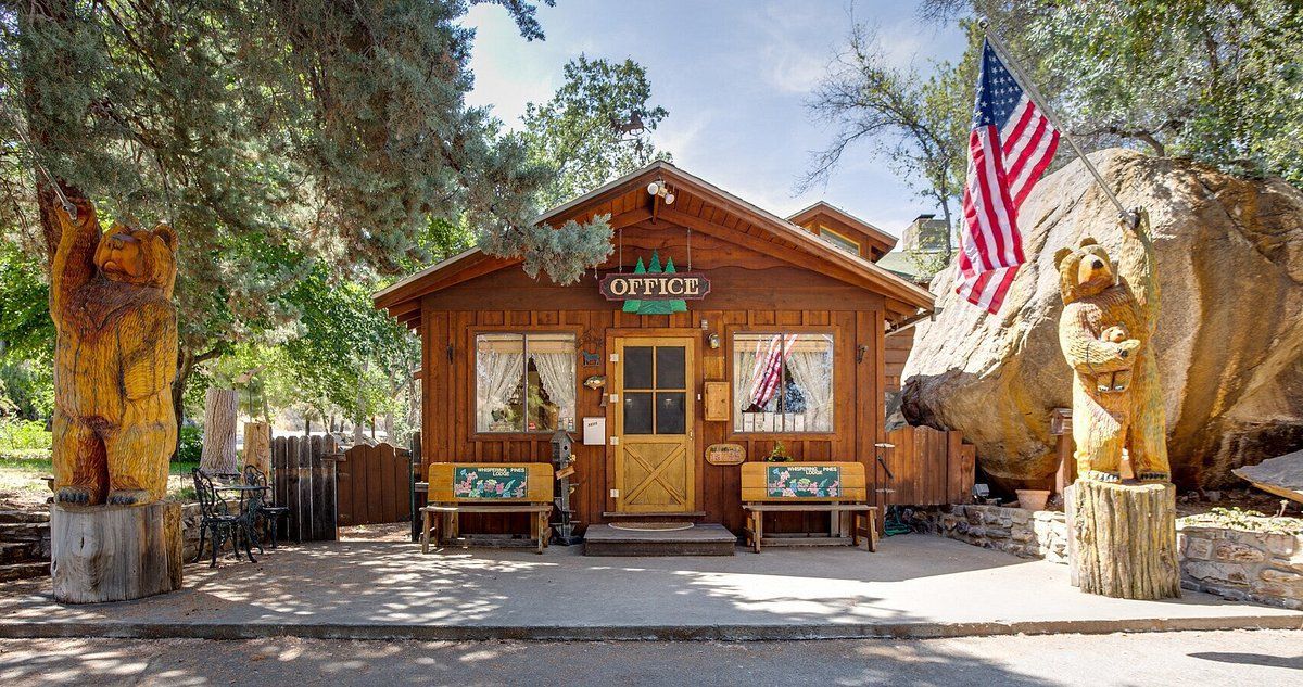 A small wooden cabin with a statue of a bear in front of it.