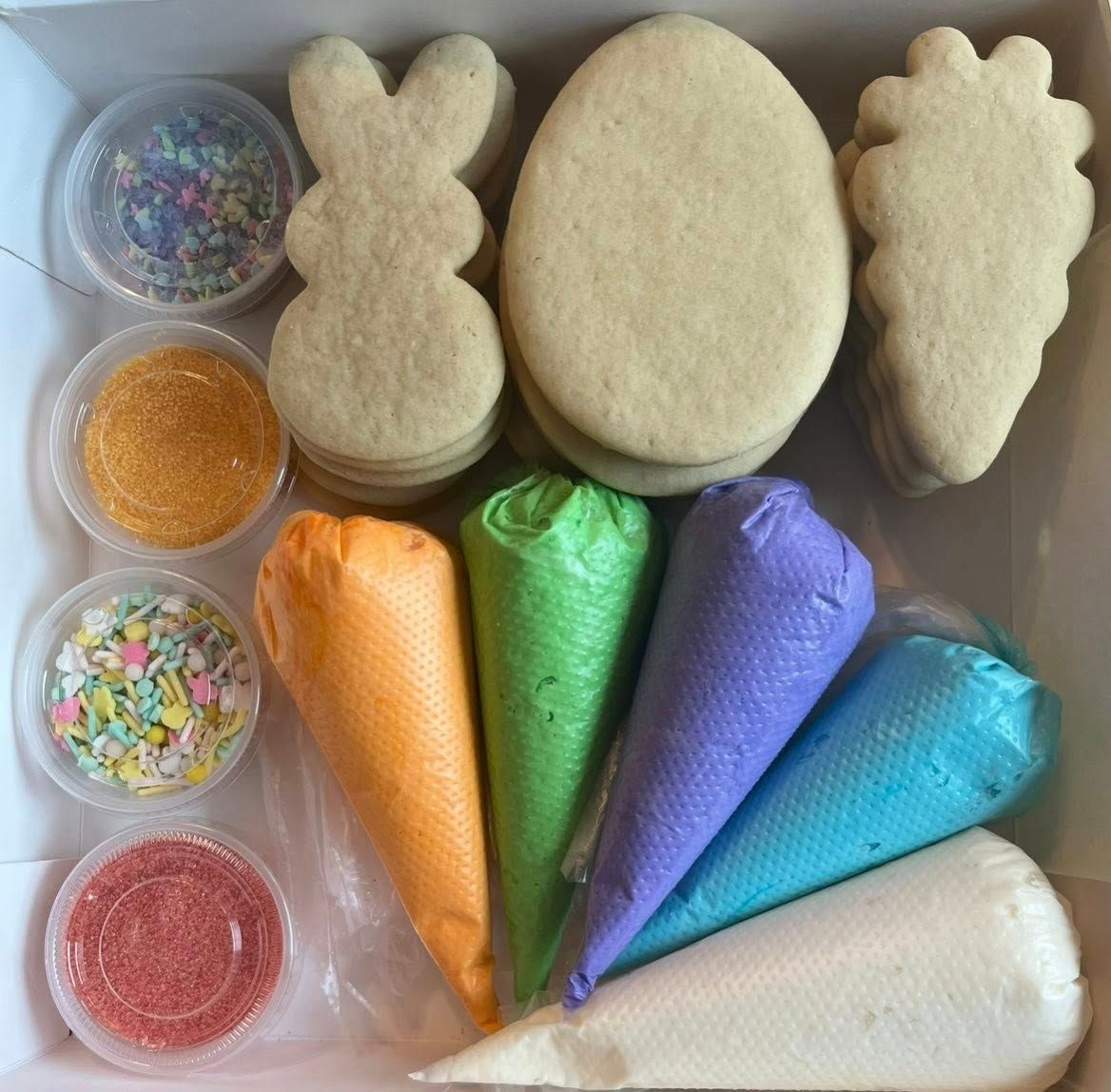 Cookie decorating kits in open cardboard boxes, with cookies, icing bags, and sprinkles visible.